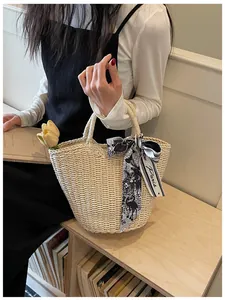 Detail of woven straw tote bag featuring a floral Paris scarf and a yellow tulip