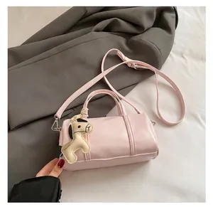 Detail of light pink Boston bag with pony charm on a stylish grey blazer background
