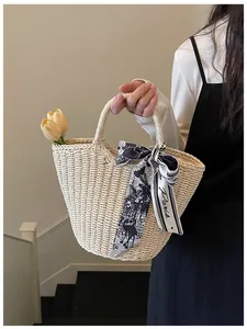 Detail of woven straw tote bag featuring decorative black and white Paris print silk scarf