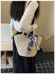 Close-up of woven straw tote bag with elegant silk scarf and floral decorative detail