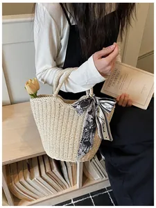 Detail of woven straw tote bag with decorative Paris print scarf and flower accents