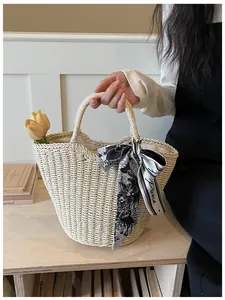 Detail of hand-woven straw tote bag with a Paris print silk scarf on the handle