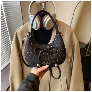 Detail van zwarte maanvormige tas met zilveren sterren, strik en metallic logo