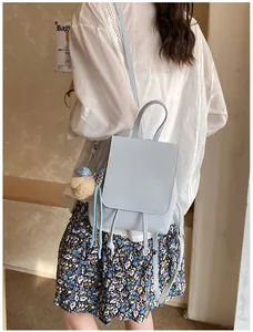 Close-up of light blue leather mini backpack with drawstring and plush bear charm detail