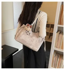 Détail d'un grand sac cabas beige avec breloque ours porté par un mannequin de dos