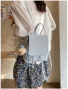 Light blue faux leather mini backpack featuring a plush bear charm and drawstring closure