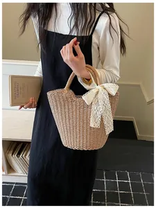 Detail of hand-woven straw tote bag featuring a large white lace bow decoration