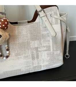Gros plan sur le sac cabas en tissu texturé crème avec finitions en cuir et ours