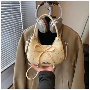Detailopname van beige maanvormige tas met sterpatronen en decoratieve strikdetails
