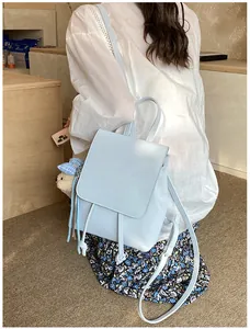 Detail of light blue faux leather backpack with drawstring closure and plush bear charm