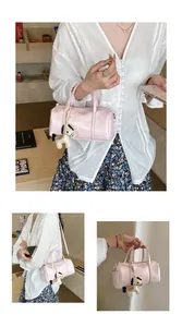Dettaglio borsa Boston in pelle rosa con doppi manici e ciondolo a cavallo