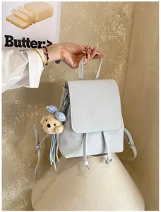 Detail of a mini light blue faux leather backpack with drawstring and cute bear charm