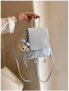 Detailed view of light blue mini backpack with bear charm and drawstring closure