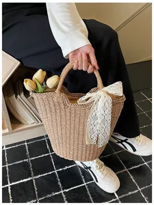 Detail of hand-woven straw tote bag with white lace bow and decorative yellow tulips