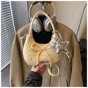 Detail van gele hobo tas met sterrenprint, strik en glinsterende sterrenhanger accessoire