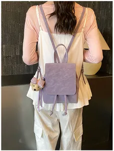 Purple faux leather backpack with drawstring flap and cute teddy bear charm on model