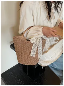 Close-up of hand-woven straw tote bag with elegant cream lace bow and round handles