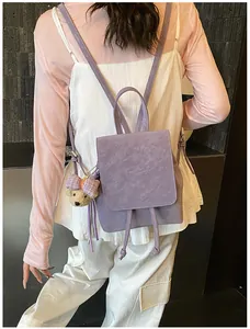 Detail view of purple faux leather backpack with drawstring flap and cute bear pendant charm