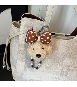 Détail d'un charmant pendentif chien en peluche avec nœud à pois sur un sac fourre-tout