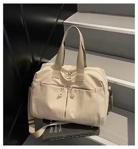 Dettaglio borsa da viaggio in tela con doppia zip frontale e tracolla larga su scale