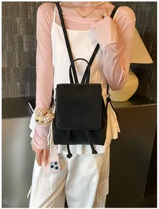 Detail of black mini backpack with drawstring closure and cute plush bear charm accessory