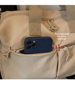 Dettaglio della tasca frontale con zip sulla borsa da viaggio beige con vano cellulare