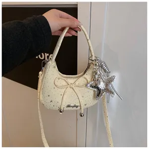 Detail van de crèmekleurige maanvormige tas met zilveren sterren en een strik