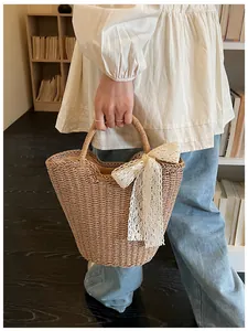Detailed close-up of a woven straw bucket bag featuring elegant white lace ribbon decoration