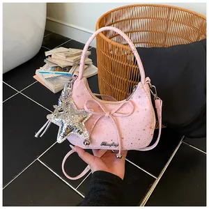 Detailweergave van de roze tas met sterpatroon, zilveren hanger en strikdecoratie