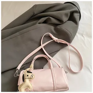 Dettaglio borsa Boston rosa con ciondolo a cavallo su una giacca grigia da ufficio