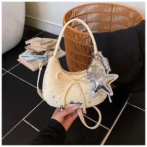 Detail van beige halve maan tas met strik, sterrenprint en zilveren sterrenhanger