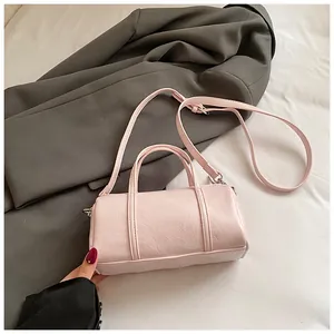 Borsa Boston cilindrica rosa con trama litchi e tracolla regolabile su blazer grigio