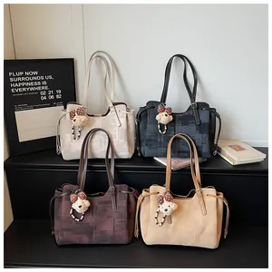 Détail de quatre sacs cabas en toile colorés avec anses en cuir et breloques ours