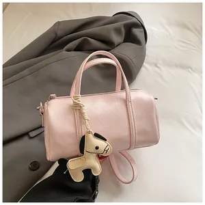 Dettaglio borsa Boston rosa con ciondolo a cavallo, doppi manici e texture in pelle venata
