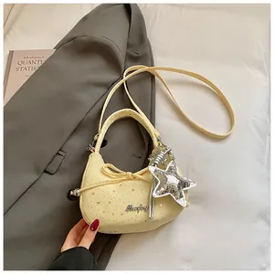 Detailopname van gele maanvormige tas met strik, sterhanger en lange schouderriem