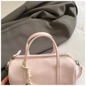 Dettaglio borsa Boston rosa con trama in pelle e ciondolo in corda intrecciata