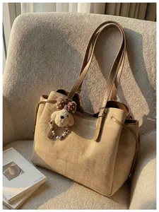 Détail du grand cabas beige avec pendentif chien en peluche sur un canapé en tissu
