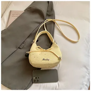 Detail van gele crossbodytas met sterren en strik naast een telefoon ter maat