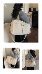 Dettaglio della grande borsa da viaggio in tela crema con tracolla e cuciture rosse