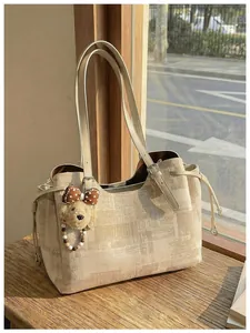Détail du sac cabas crème avec imprimé journal vintage et pendentif ours marron