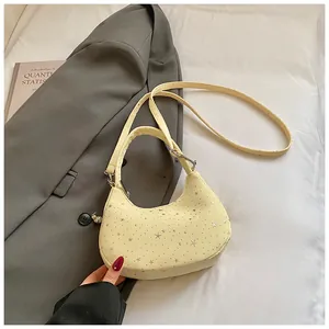Detail van lichtgele halve maan schoudertas met zilveren sterren op een grijze blazer