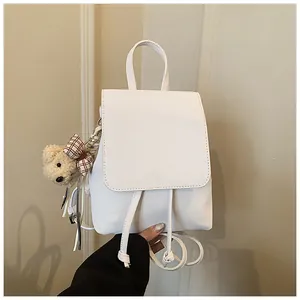 Close-up of a white PU leather mini backpack featuring a plaid bow bear charm accessory