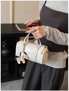 Dettaglio della borsa Boston bianca plissettata con un ciondolo in pelle a forma di cavallo