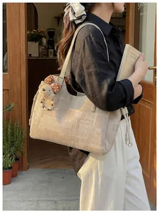 Détail du sac cabas beige à texture géométrique et breloque ours en peluche doux