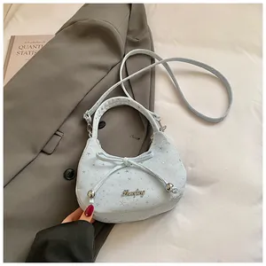 Detail van de lichtblauwe hobo-tas met zilveren sterpatronen en een strikaccent