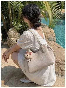 Détail d'un sac cabas en toile beige avec imprimé géométrique et charmant ourson peluche
