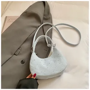 Close-up van een lichtblauwe tas met sterpatroon op een grijs jasje en boek