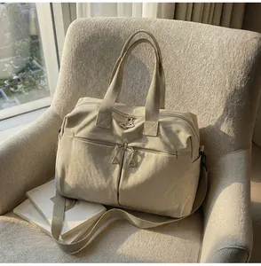 Dettaglio della borsa da viaggio in tela beige con cerniere in metallo e cuciture rinforzate