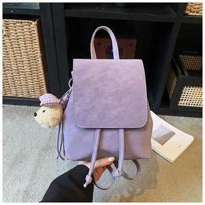 Detail of lavender mini backpack in matte leather featuring a cute plush bear charm