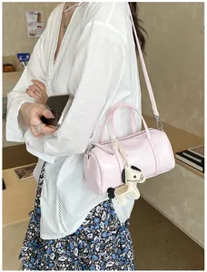 Borsa Boston rosa a cilindro con ciondolo a cavallo su tavolo di legno al caffè